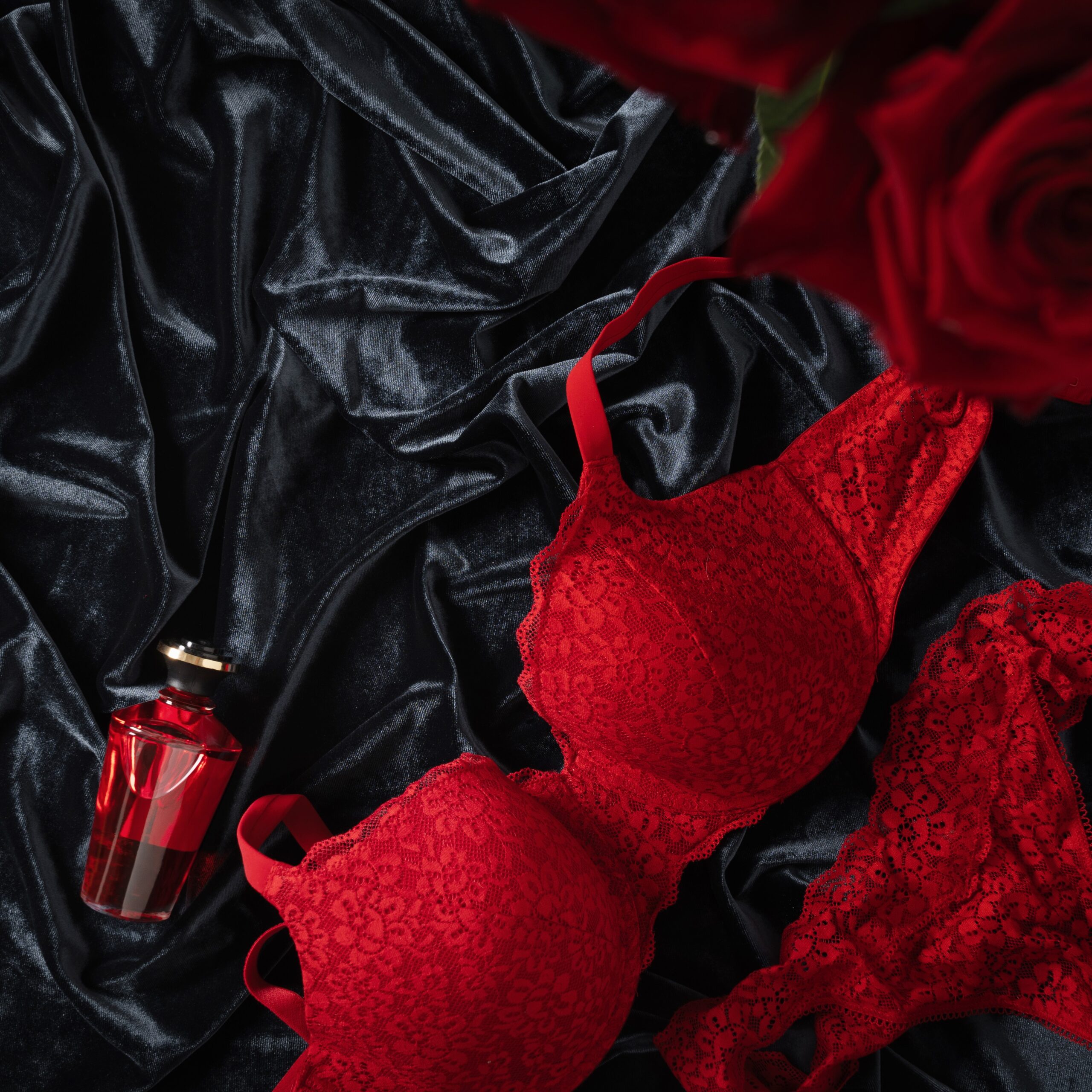Lace women's red underwear, lingerie and red roses for Valentine's day on dark. Romantic dating. View from above. Copy space.